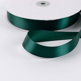 Dark green satin ribbon spool on white background
