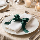 Elegant table setting with white napkin and green ribbon on dinner plate