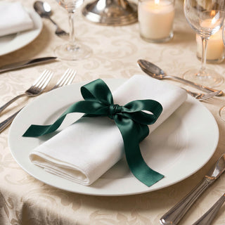 Elegant table setting with white napkin and green ribbon on dinner plate