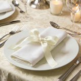 Elegant white plate with folded napkin and ribbon on a formal dining table