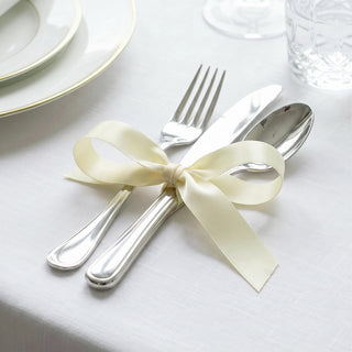 Elegant silver cutlery tied with cream ribbon on a white table setting