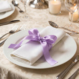 Elegant table setting with white napkin tied by purple ribbon on dinner plate