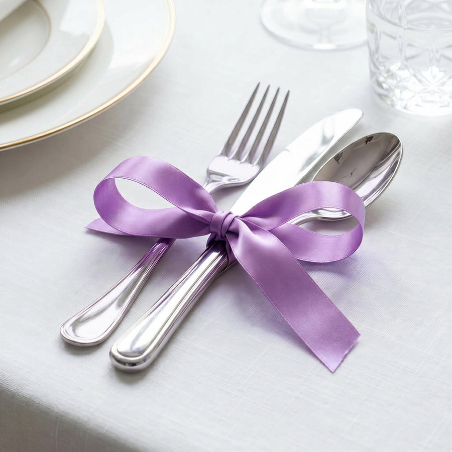 Purple ribbon tied around silver cutlery on a white table setting