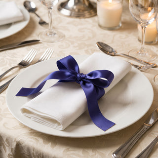 Elegant table setting with white plate, napkin, and purple ribbon bow