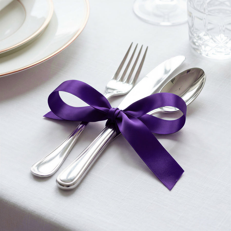 Elegant silver cutlery tied with purple ribbon on white table setting