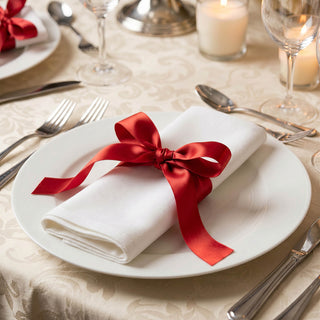 Elegant wedding table setting with white napkin and red ribbon on plate