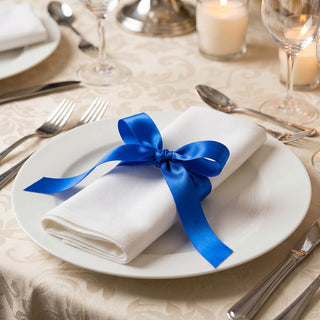 Elegant place setting with white napkin tied in blue ribbon on dinner plate