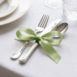 Elegant table setting with silver cutlery tied with green ribbon bow