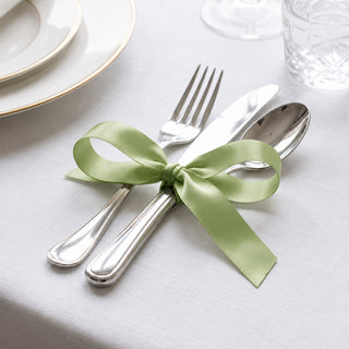 Elegant table setting with silver cutlery tied with green ribbon bow