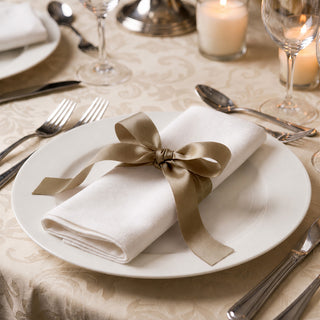Elegant white napkin with gold ribbon on formal dining table setting