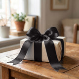 Wrapped gift box with black satin ribbon on a wooden table
