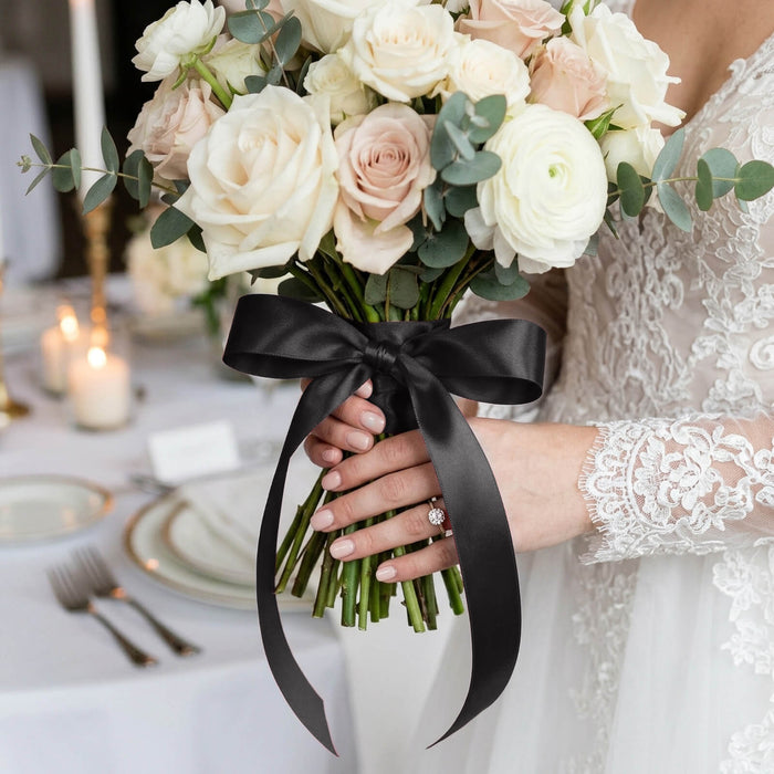 Bride holding ivory rose bouquet with black ribbon at wedding reception