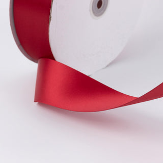 Red satin ribbon roll close-up on white background