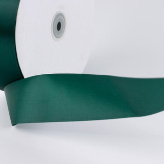 Green satin ribbon spool on white background