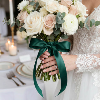 Bride holding ivory rose bouquet with eucalyptus and dark green ribbon