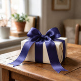 White gift box with a purple ribbon bow on a wooden table
