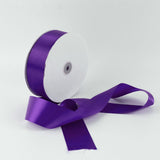 Purple satin ribbon roll with loose ribbon on a white background