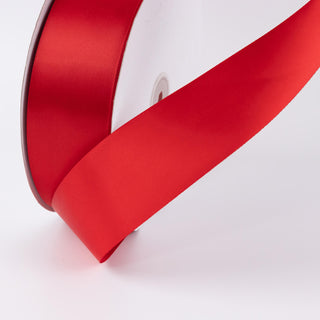 Red satin ribbon roll with wide decorative ribbon on white background