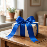 White gift box with blue ribbon bow on wooden table