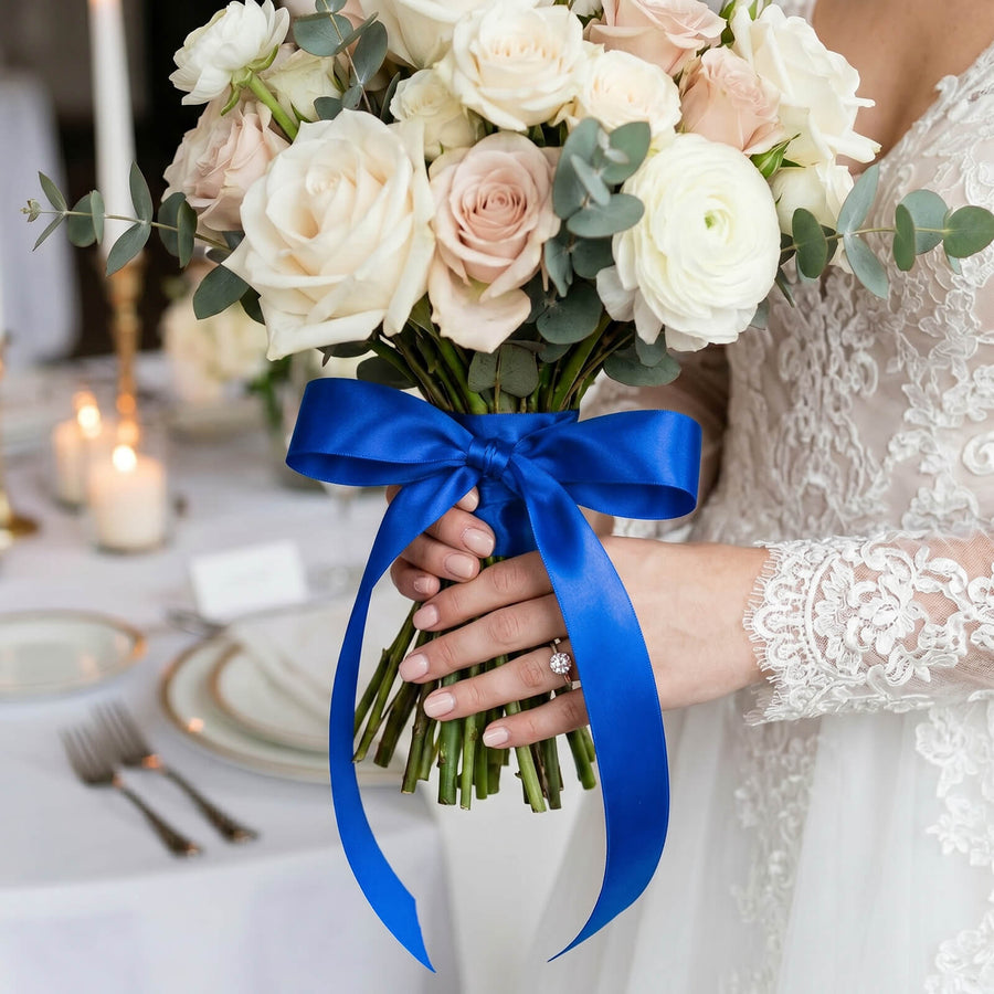 Bridal bouquet with white roses, eucalyptus, and blue ribbon in wedding dress