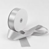 Silver satin ribbon spool with loose ribbon on white background