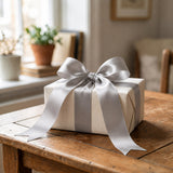 Gift box with silver ribbon bow on wooden table indoors