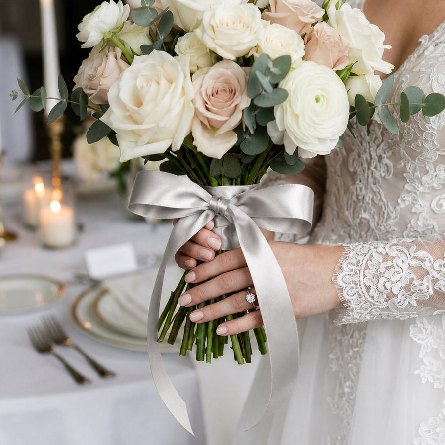 Bride holding white rose and eucalyptus wedding bouquet with silver ribbon