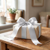 Gift box with white ribbon on wooden table in a cozy room
