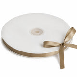 White satin ribbon spool with gold trim and bow on a white background