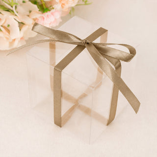Transparent gift box with gold ribbon bow on soft floral background