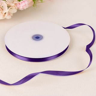 Purple satin ribbon spool on a white table with soft floral background