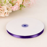 Purple satin ribbon spool on white table with soft floral background