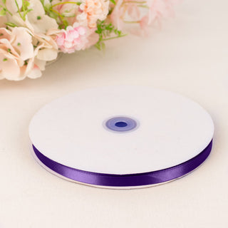 Purple satin ribbon spool on white table with soft floral background