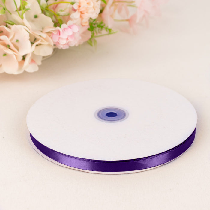 Purple satin ribbon spool on white table with soft floral background