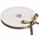 White satin ribbon spool with gold bow on a white background