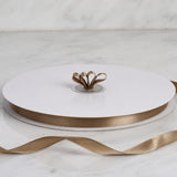 White ribbon spool with gold satin ribbon roll on marble surface