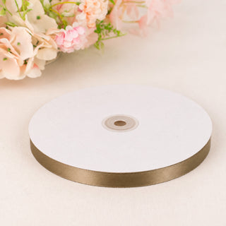 Gold satin ribbon spool on white background with pastel flowers