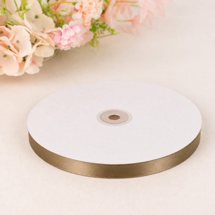 Gold satin ribbon spool on white background with pastel flowers