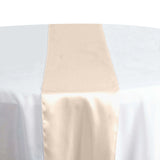 Elegant beige table runner on a round table set for dining.