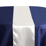 Elegant satin table runner on a navy tablecloth with dinnerware setting. 