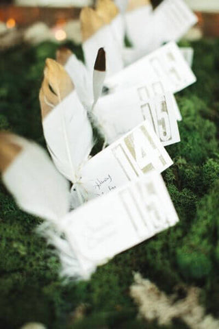 Feather place cards on moss and greenery