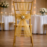 Gold chiavari chair with a sheer gold bow and floral accent.