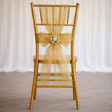 Gold chiavari chair with a yellow tulle bow and floral embellishment.