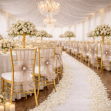 Elegant wedding reception setup with floral centerpieces and gold chairs.