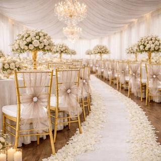 Elegant wedding reception setup with floral centerpieces and gold chairs.