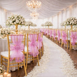 Elegant wedding reception with gold chairs and pink bows, adorned with floral arrangements.
