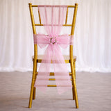 Gold chiavari chair with pink organza bow and floral accent.