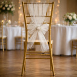Gold chiavari chair with white tulle bow at an elegantly decorated event.