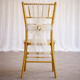 Gold chiavari chair with a white bow and floral accent.