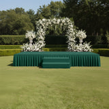 Elegant floral arch on a green stage in a garden setting.
